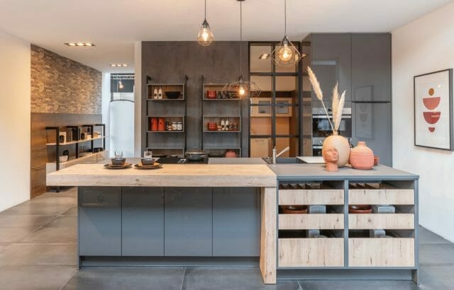 Grey handleless kitchen island with reclaimed wood top and open bottle storage, styled with warm pendant lighting