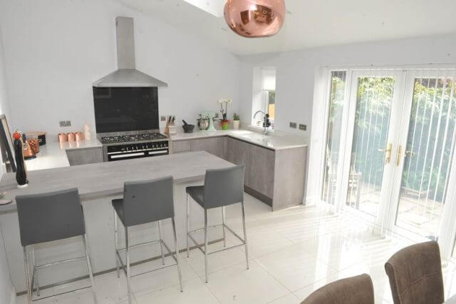 Light grey kitchen with breakfast bar and range cooker by Tolle Kitchens