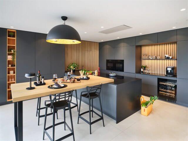 Contemporary grey kitchen with wood breakfast bar and feature wall panelling