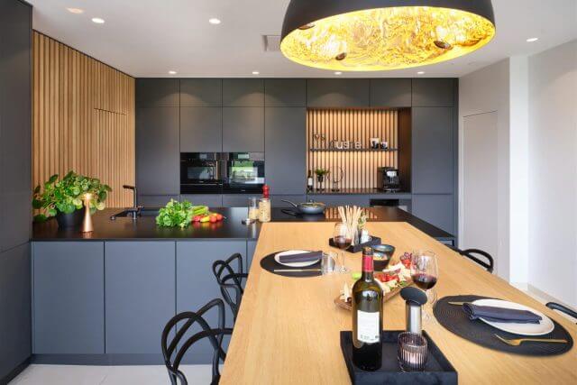 Modern grey kitchen with wooden dining island and statement pendant light