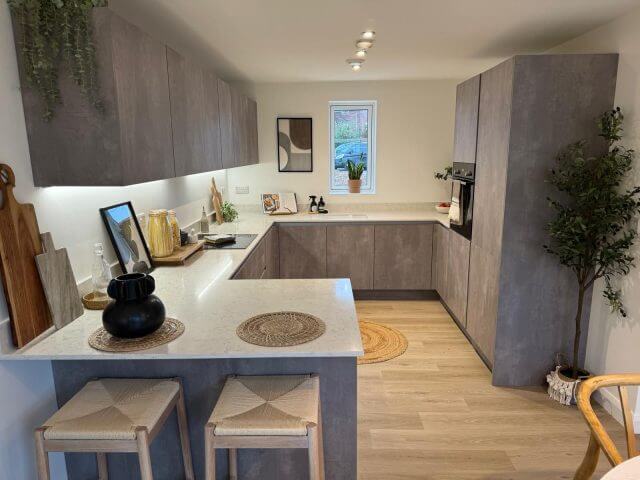 Contemporary U-shaped kitchen with textured cabinetry, quartz worktops and integrated under-cabinet lighting by Tolle Kitchens