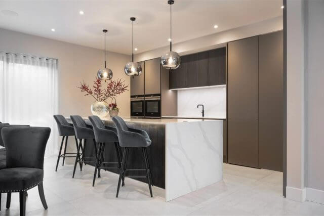 Modern dark kitchen with marble-effect island, breakfast bar and pendant lights