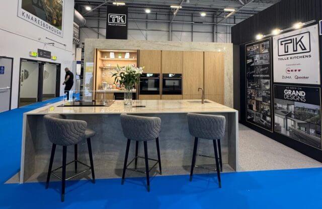 Tolle Kitchens exhibition stand at the Homebuilding and Renovating Show featuring a concrete-effect island with bar stools