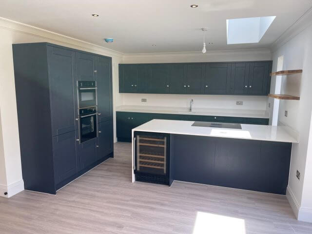 Dark shaker kitchen with white island, integrated oven and wine cooler
