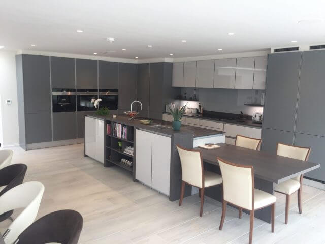 Bespoke handleless grey kitchen with central island and integrated dining table, designed by Tolle Kitchens