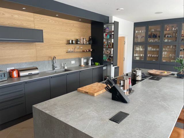 Contemporary kitchen with dark cabinetry, wood wall cabinets and large stone island