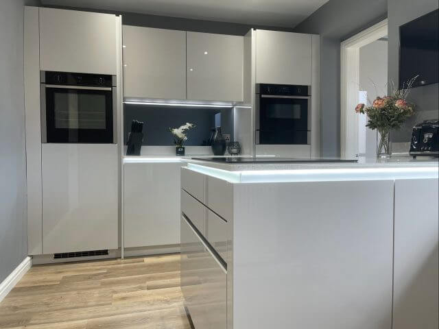 Gloss white handleless kitchen with illuminated island and integrated ovens