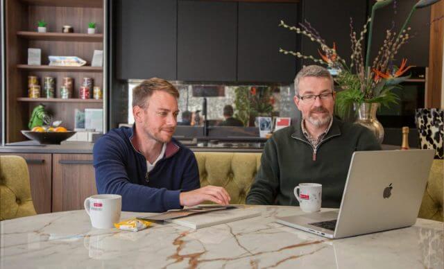 Tolle Kitchens designers consulting with a client over kitchen plans at a marble worktop table